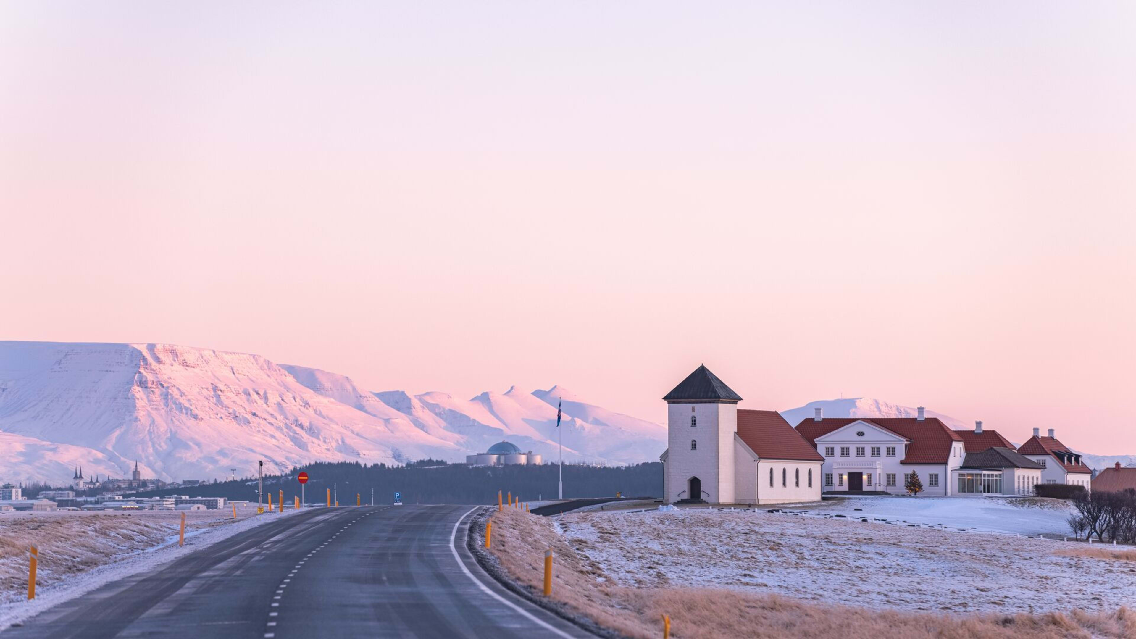 houses along iceland road under pink sky