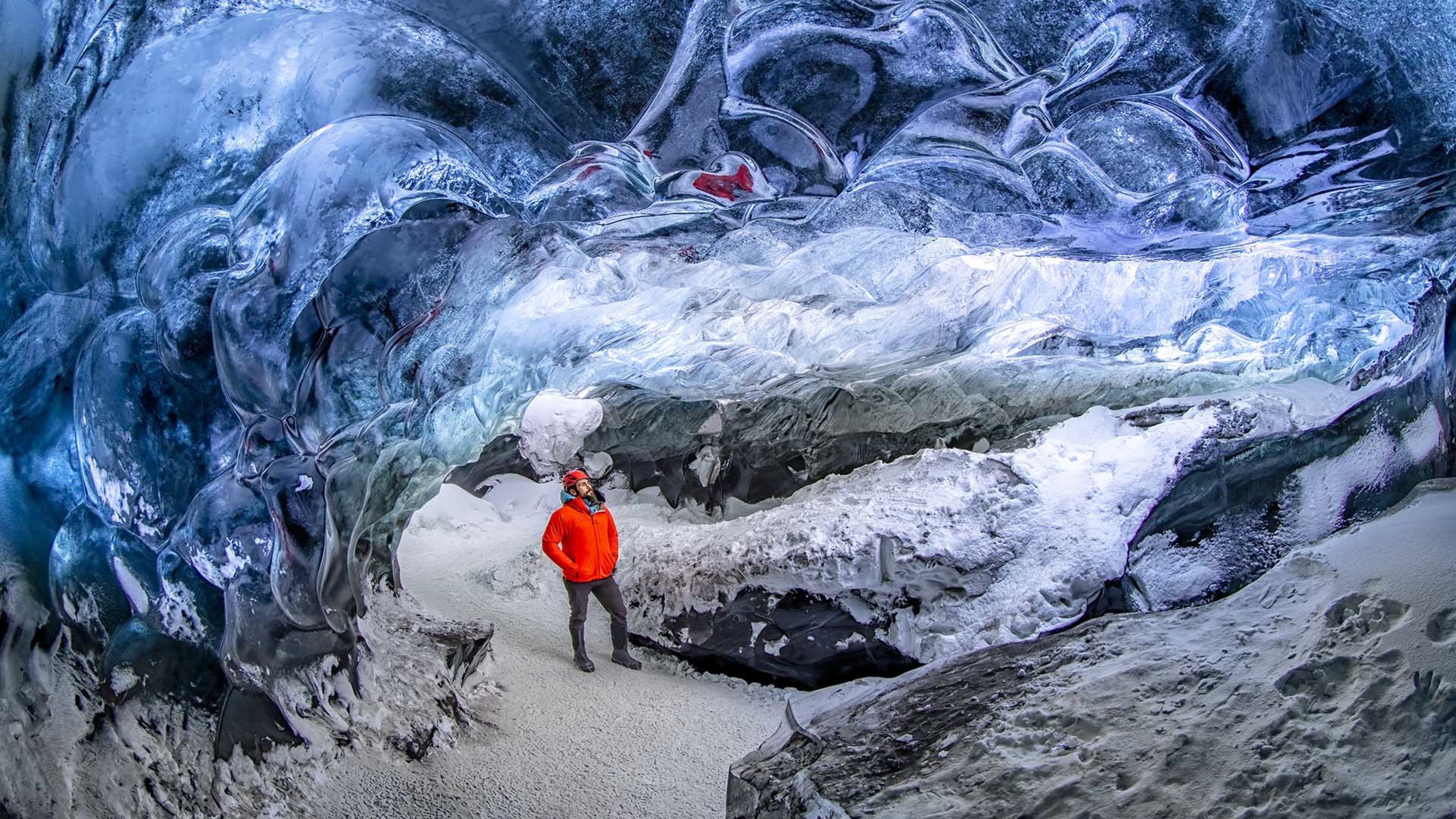 people staring at the ice wall of blue ice cave