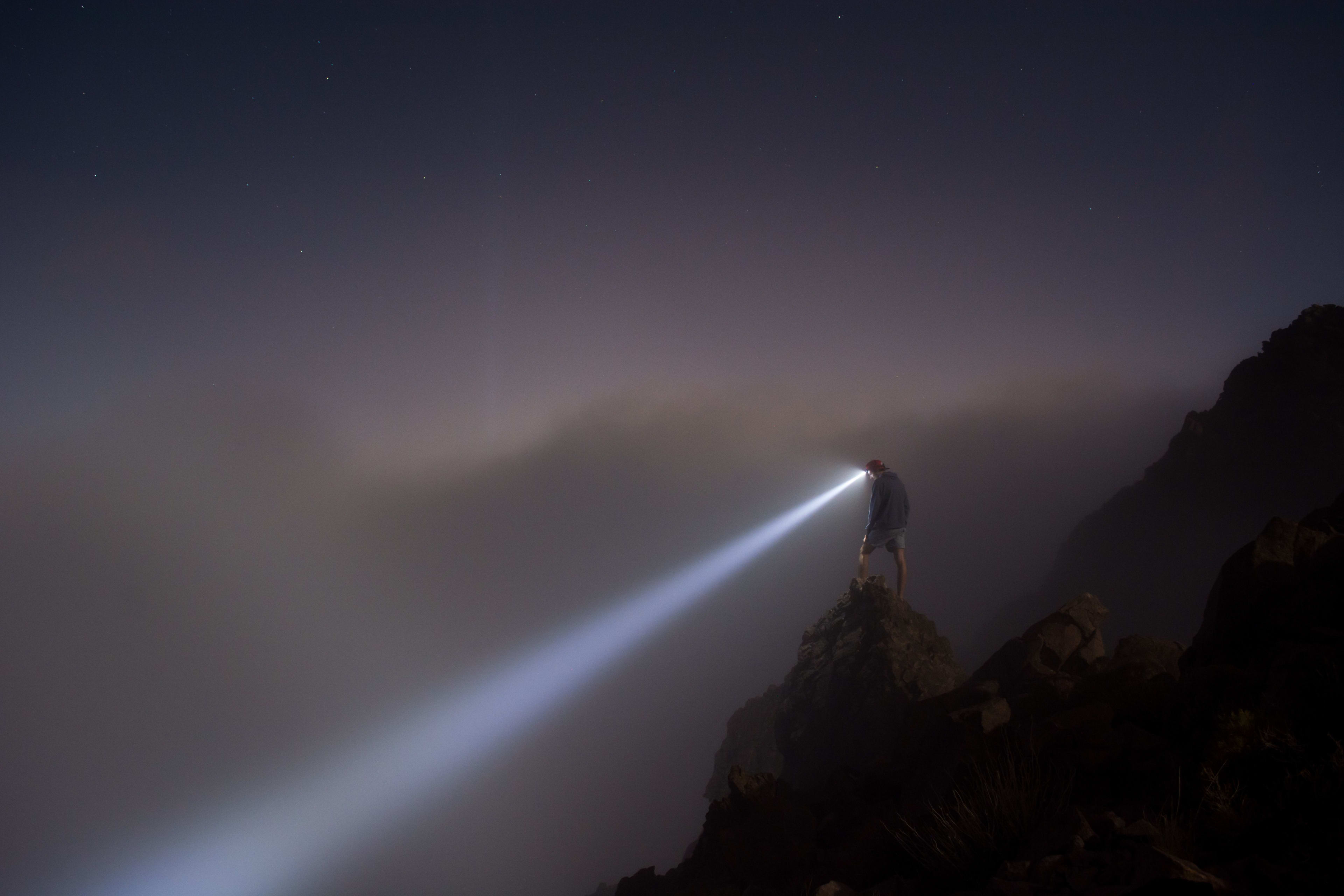 man on cliff with flashlight open
