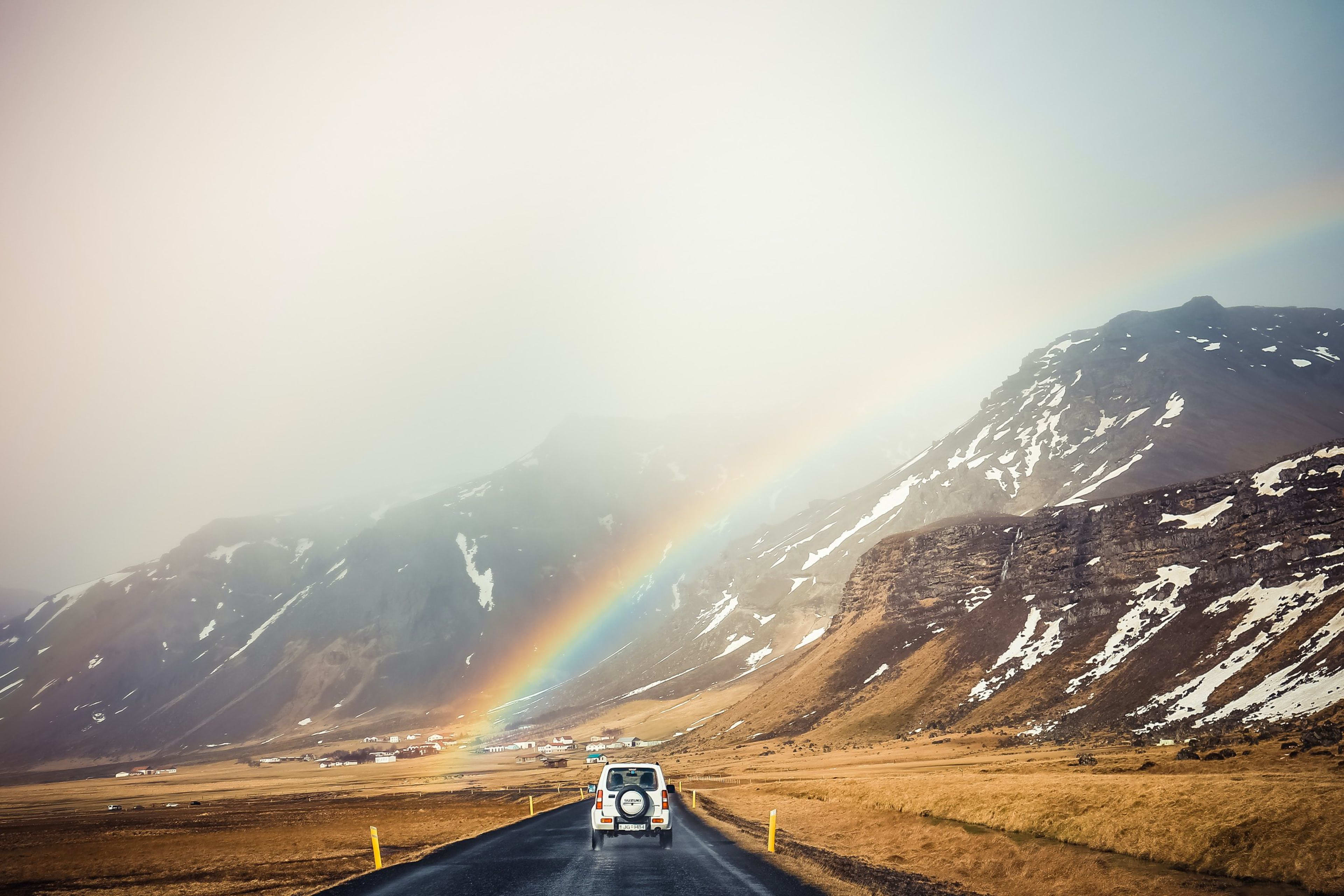 driving on iceland road with rainbow