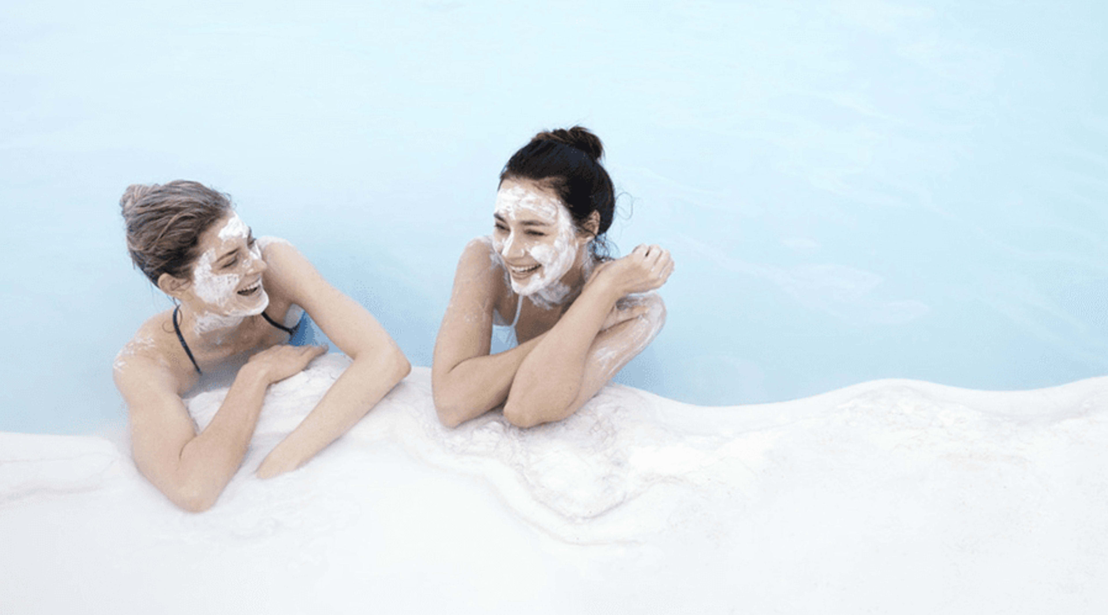 women bathing in blue lagoon with silicone mud mask