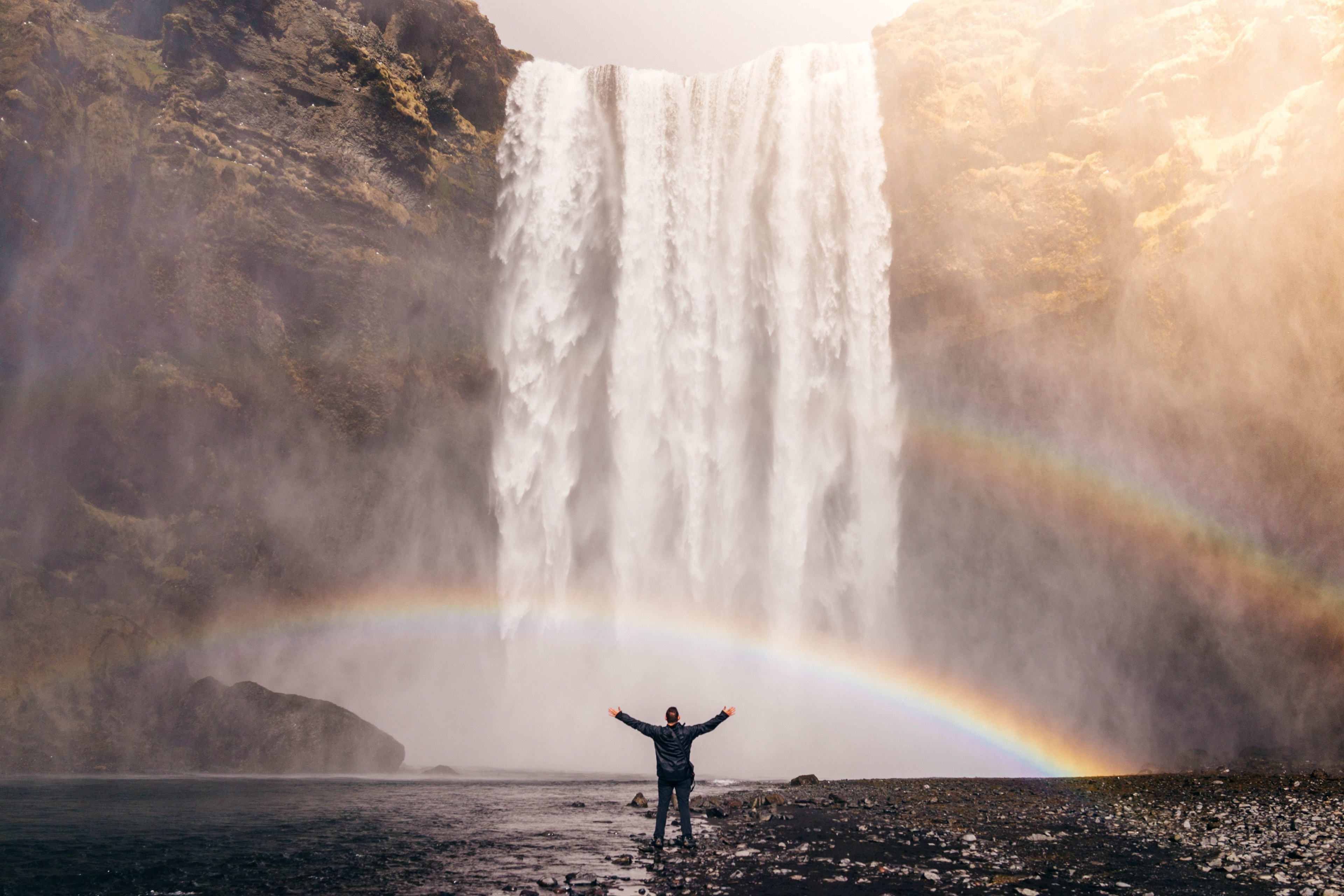 people standing in front of double rainbow of skogafoss